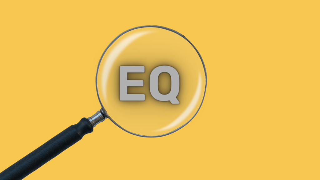 This is an image of a magnifying glass with EQ in the lens and a yellow background. It signifies searching for the signs of emotional intelligence.